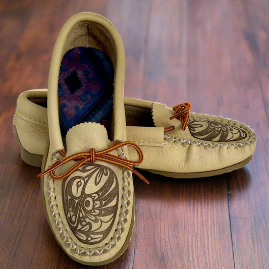 Pair of beige moccasin shoes with decorative patterns on a white background