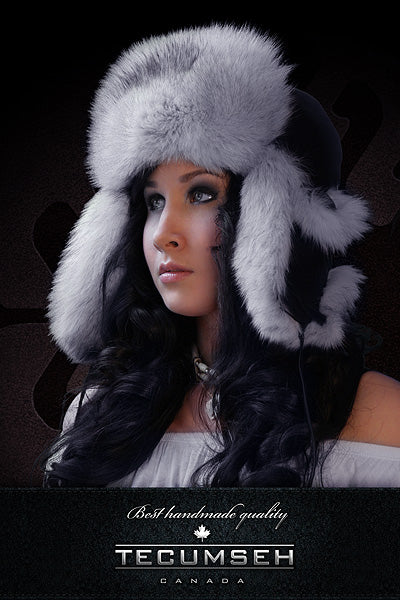 Woman wearing a gray fur hat with ear flaps against a dark background