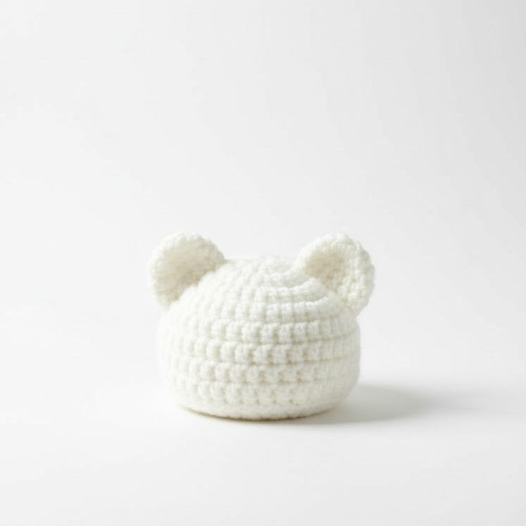 White knitted bear-shaped beanie on a white background