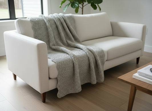 White sofa with a textured gray throw blanket in a modern living room.