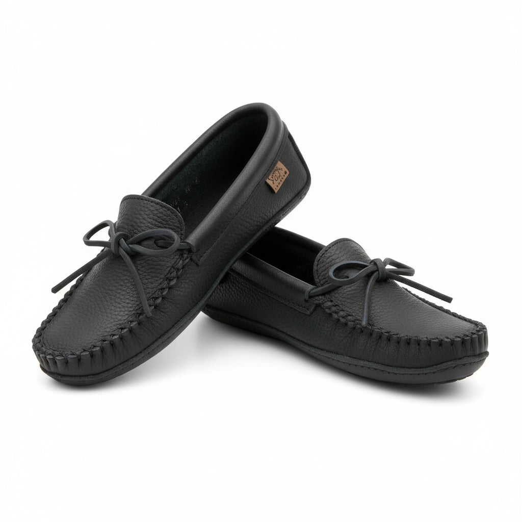 Pair of black moccasin slippers on wit a white background 
