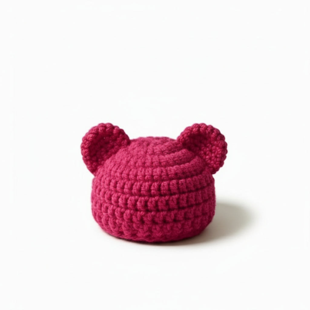 Pink crocheted hat with ears on a white background