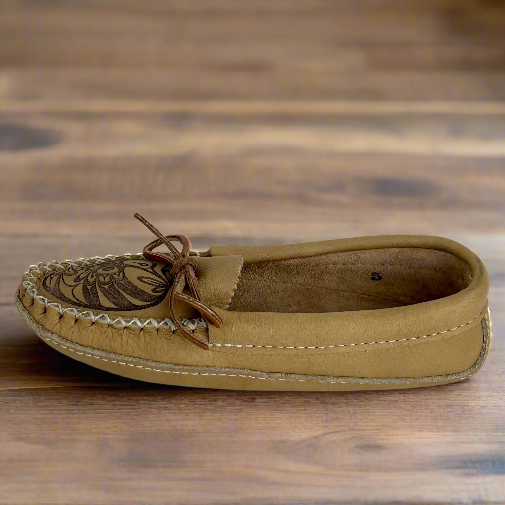 Tan moccasin shoe with brown laces on a wooden surface