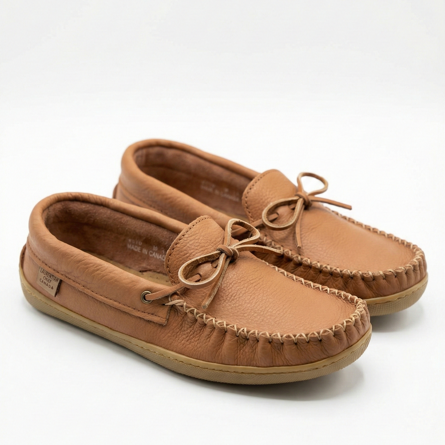 Pair of tan moccasin shoes on a white background