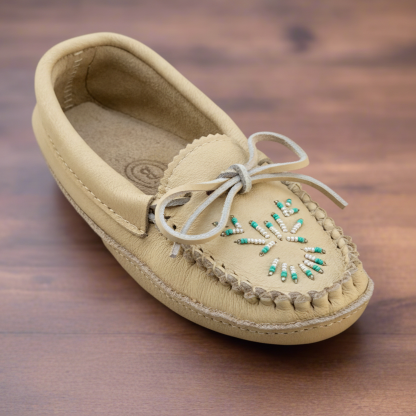 Beige moccasin shoe with decorative elements on a wooden surface